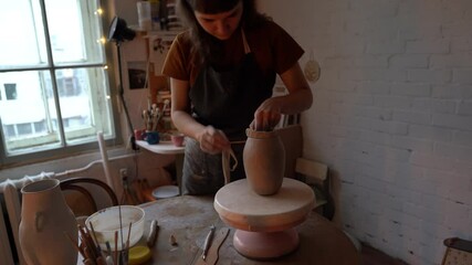 Poster - Creative young woman making vase or jug of raw clay in workshop. Female artist prepare handmade ceramic pottery for baking in art studio space. Small business, artistic hobby and entertainment concept