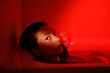 Portrait in red neon light of young sensual asian woman relaxing in bath at home, female looking at camera while lying in clothes in bathtub full of water, suffering from hangover or drug comedown