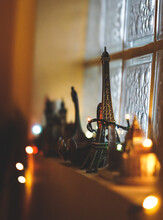 Selective Focus Of A Small Eiffel Tower Souvenir On The Windowsill Decorated With Lights
