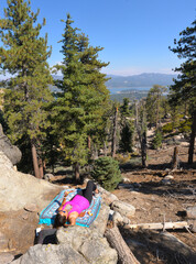 Wall Mural - Vertical shot of a female lying on the blanket in the forest under a blue clear sky