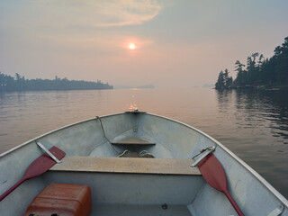 Poster - Beautiful view of a boat on a lake, pine trees on the sunset sky background