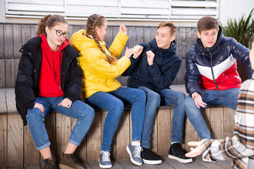  Four cheerful teenage friends having fun while spending time together outdoors on warm spring day