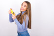 Nice addicted cheerful Young caucasian girl wearing blue turtleneck over white background using gadget playing network game