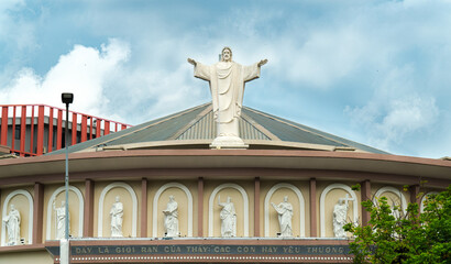 Beautiful view of the statue of Jesus on the top of a building under a cloudy sky in Vietnam