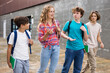 Group of four teens going from school together and talking.