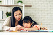 © Art_Photo - Portrait happy love asian family mother teach little daughter asian girl learn and study on table.Mom and asian young girl writing with book and pencil making lessons in homeschool at home.Education