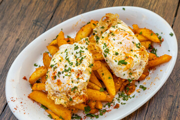 Sticker - Top view of French fries with egg pashot served in a white plate on a wooden table