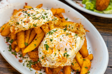 Poster - Closeup of French fries with egg pashot served in a white plate on a wooden table