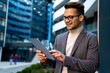 © NDABCREATIVITY - Happy young business man with tablet at work in modern urban background