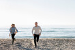 © Westend61 - Man and woman running on sand at beach