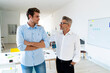 © Westend61 - Businessman with hand in pocket talking to colleague standing at office