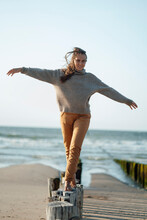 Young Woman Balancing On Wooden Posts At Beach