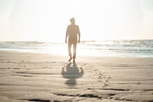 Senior Man Walking Towards Sea At Beach On Sunny Day