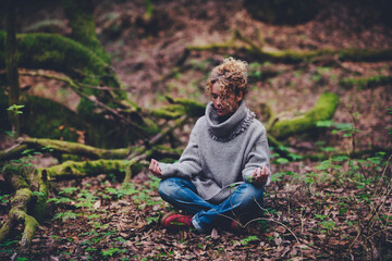 Wall Mural - Woman sit down outdoor in the middle of nature and forest woods meditate in lotus yoga position with closed eyes Mindfulness and nature connection people. Female lady have relax and care her lifestyle