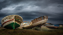 Wreckage Of Old Fishing Boats Stranded On The Beach Against The Backdrop Of A Stormy Cloudy Sky