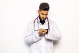 Fototapeta Na drzwi - Indian doctor pointing at watch with serious expression as wasted time concept on white studio background