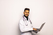 © F8  \ Suport Ukraine - Young middle east doctor standing with Stethoscope and laptop. Young Doctor man with Beard and happy face. Healthcare concept.