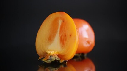 Poster - ripe cut half persimmon isolated on black