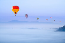 Beautiful Hot Air Balloons Flying Above Foggy Landscape In Morning ,green Mountain In Nature With Blue Sky Background.