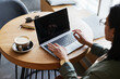© Seventyfour - Close up of young Asian woman using laptop in cafe while working remotely in elegant wooden interior, copy space