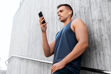 Poster - fitness, sport and technology concept - young athlete man with earphones and smartphone listening to music outdoors