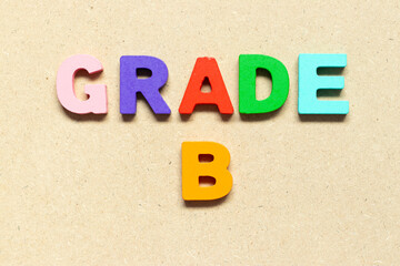 Color alphabet letter with word grade B on wood background