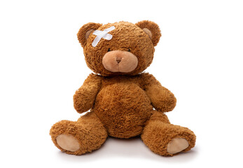 medicine, healthcare and childhood concept - teddy bear toy with medical patch on head on white back
