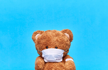 Wall Mural - vaccination, healthcare and pandemic concept - teddy bear toy in protective medical mask with patch on paw over blue background