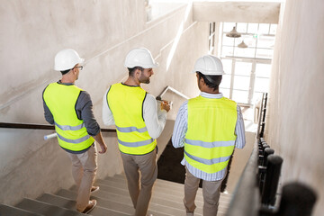 Sticker - architecture, construction business and people concept - male architects in helmets with blueprints and clipboard walking downstairs at office building