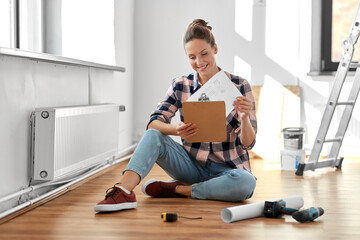 Poster - repair, people and real estate concept - woman with clipboard sitting on floor at home