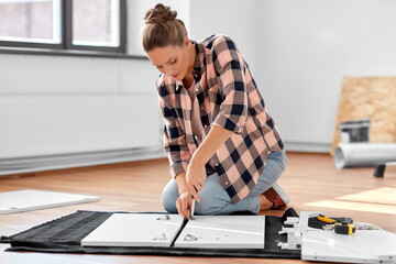 Wall Mural - repair, improvement and furniture concept - woman with screwdriver assembling locker at home