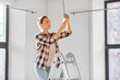 moving, electricity and repair concept - woman changing light bulb at new home