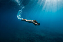 Freediver Woman In Bikini With Fins Dive Underwater In Deep Blue Sea.
