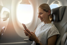 Young Woman Using Mobile Phone During The Flight In The Airplane