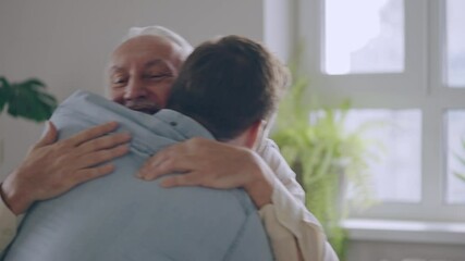 Wall Mural - Happy senior father and adult son hugging on couch, family love and support