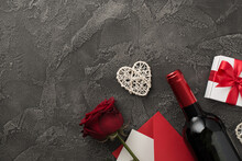 Top View Photo Of Saint Valentine's Day Decorations Wine Bottle White Giftbox With Bow Rattan Heart Envelope With Card And Red Rose On Isolated Textured Dark Grey Concrete Background With Copyspace