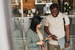 © Seventyfour - High angle portrait of smiling African-American man talking to young woman while standing in cafe doorway