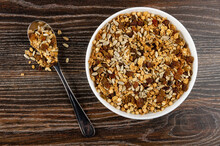 Spoon With Granola, Muesli With Cereals, Raisin And Sunflower Seeds In Plate On Table. Top View