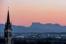 Beautiful Sunset Over French Vercors Mountains With The Snow On The Top And A Church Tower Of The Cornas Village On The Foreground.