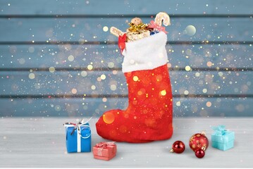 Sticker - Stuffed Santa Claus boot with sweets and gingerbread man in the snow. Cute rustic background