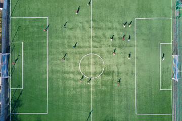 Aerial view of soccer players playing football on green sports stadium