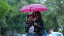 Two Friends Together During Rainy Day, Person Opening Umbrella Covering Friend In Rain In Street