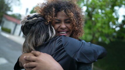 Wall Mural - Girlfriends embrace and hug. Two diverse women hugging outside