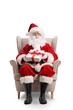 © Ljupco Smokovski - Full length portrait of santa claus sitting in an armchair with a present in his hands