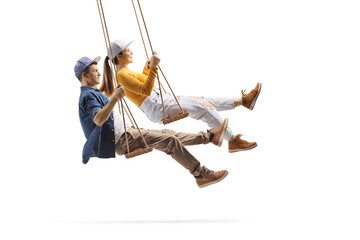Wall Mural - Profile shot of male and female teens swinging on wooden swings
