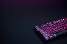 Close-up Of Purple Backlighted Gaming Computer Keyboard Against Dark Background.