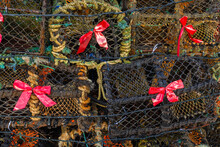 Red Bow Attached To An Old And Used Fish And Crab Traps In A Harbor. Event Celebration. Tribute To Rough Fisherman Job. Christmas Theme Abstract Tree.