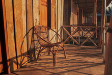 Rattan Chair Outside A Wooden Porch In The Sunset Light