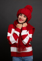 Wall Mural - Close up portrait of a beautiful smiling stylish woman in winter hat and scarf while she posing and having fun isolated on gray background