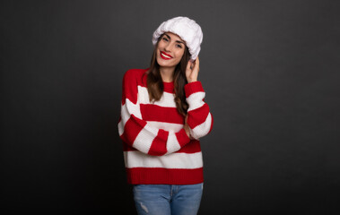 Wall Mural - Close up portrait of a beautiful smiling stylish woman in white winter hat while she posing and having fun isolated on gray background